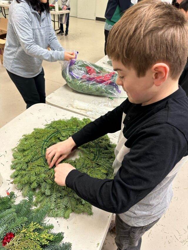boy assembling wreath at donation event